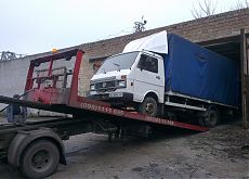 Грузовой автомобиль затягивается на платформу эвакуатора с помощью лебедки